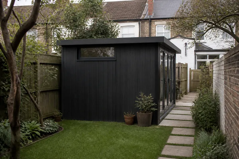 A compact flat-roofed garden room in a small terraced-house garden
