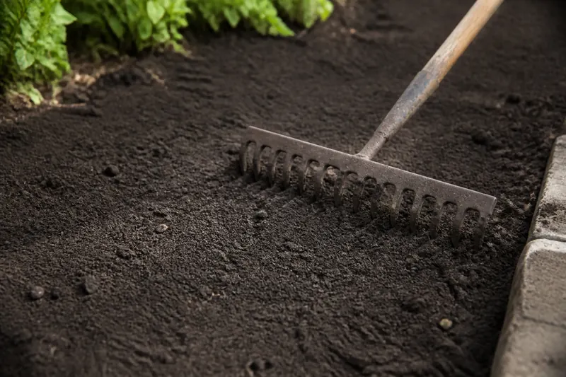 Dark screened topsoil being raked level